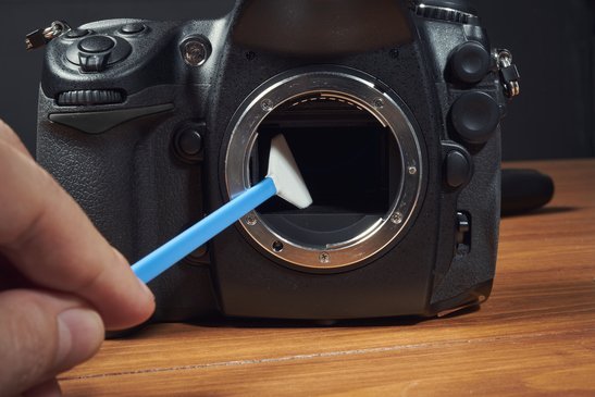 Brush for cleaning digital camera with hand on wood table